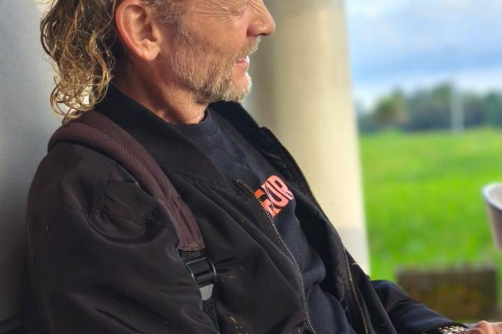 Souvereign seated in a black robe on a porch overlooking rice fields at dusk, in quiet reflection