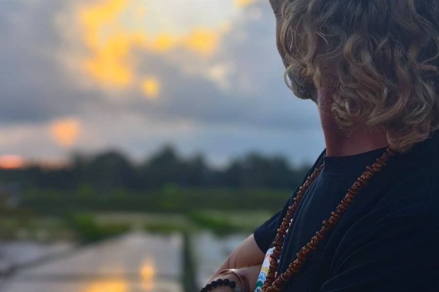 Souvereign standing arms crossed in a reflective rice paddy at golden hour sunset, alternate angle