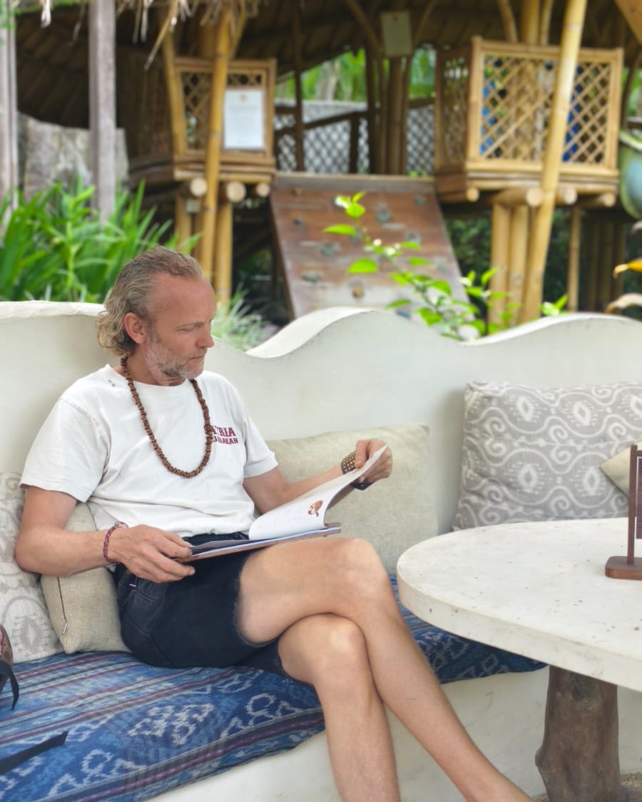 Souvereign sitting on an outdoor bamboo patio in a sarong, reading, the My Journey card on the Home page